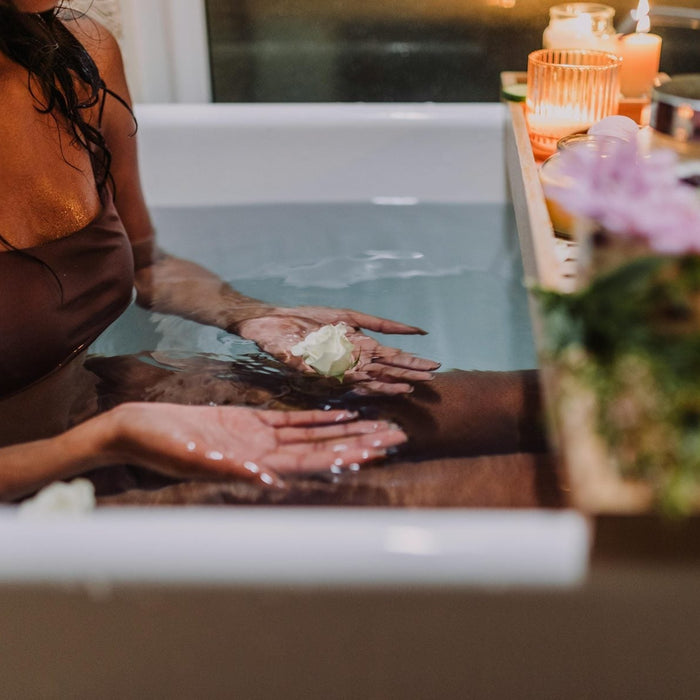 Woman relaxing in a ritual detox bath with candles and botanicals
